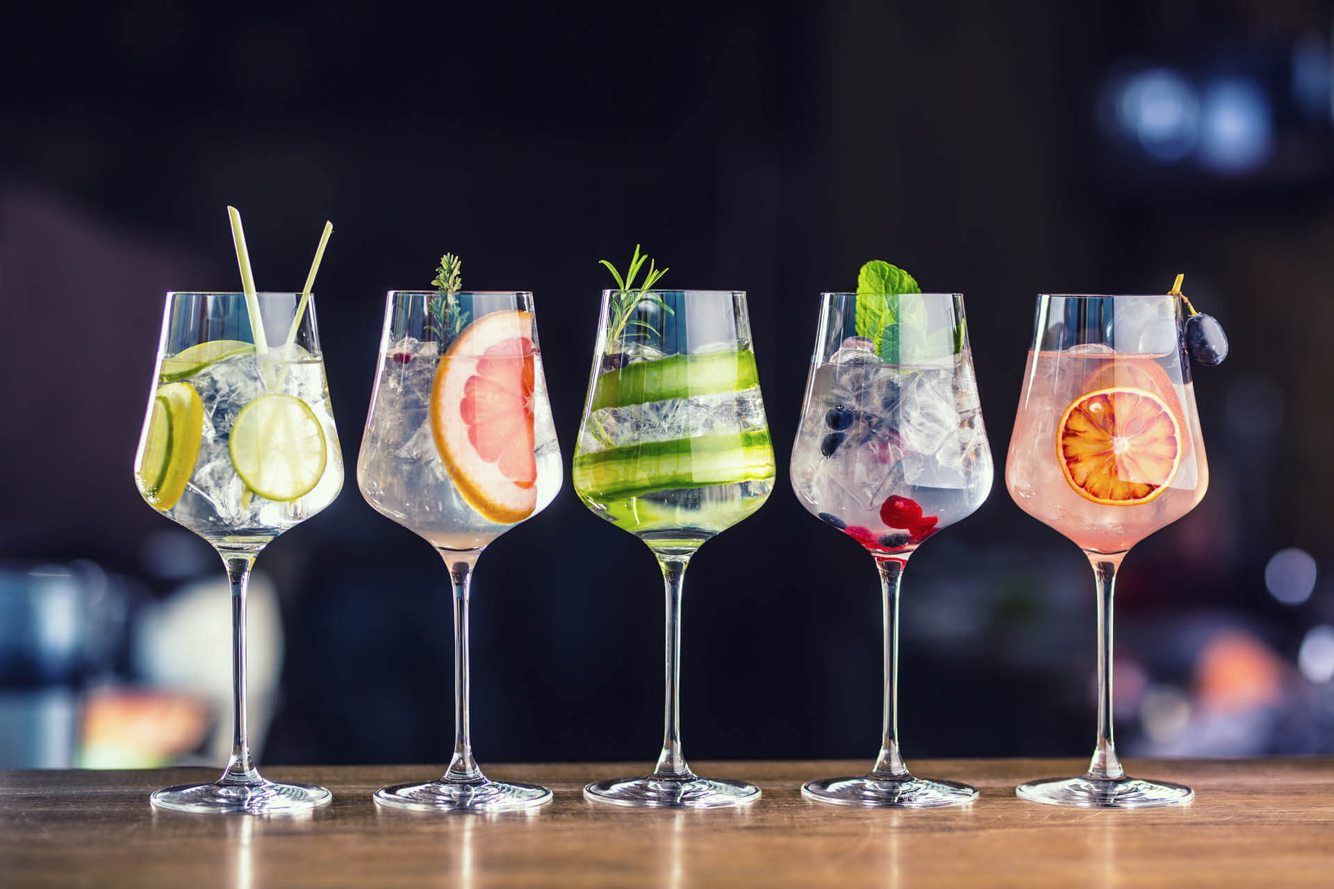 Colourful gin tonic cocktails in wine glasses on bar