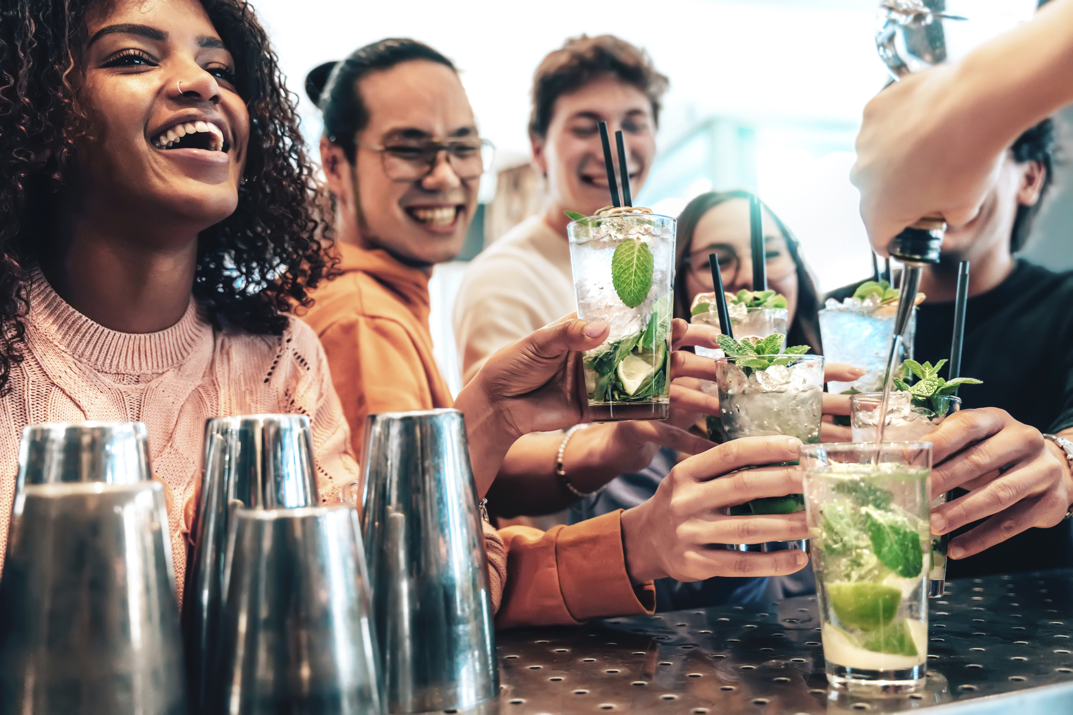 Bartender preparing cocktail mojito at pub - Happy smiling friends toasting cocktail at bar restaurant counter at happy hour time - Youth multiracial, happiness and fun lifestyle concept