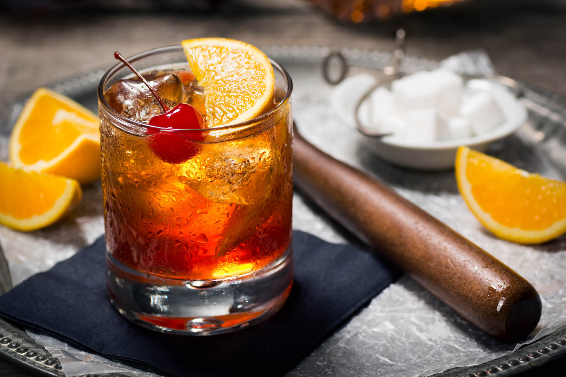 Old Fashioned cocktail with cherry, orange on tray